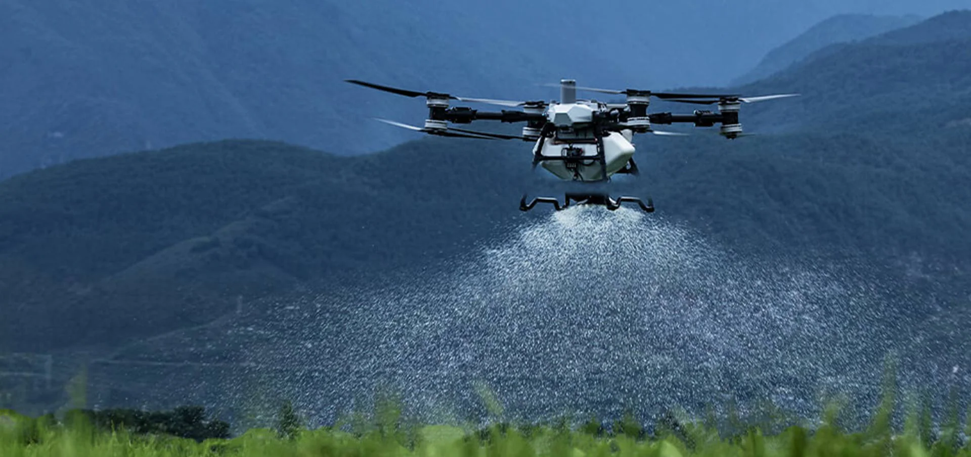 DJI Agras T100 drone spreading granular material over agricultural field